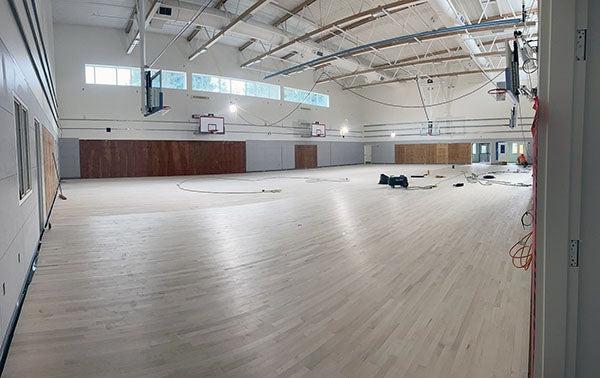 a large room with basketball hoops with a wooden floor installed halfway across